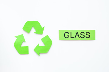 Types of matherial for reycle and reuse. Printed word glass near eco symbol recycle arrows on white background top view copy space