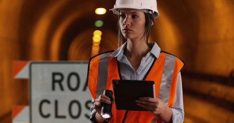 female worker shining flashlight at camera while in tunnel under construction