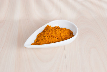 Turmeric powder and fresh turmeric on wooden background.