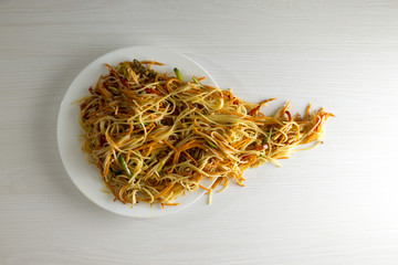Rice noodles Funchoza with vegetables in a white plate. Traditional Korean cuisine