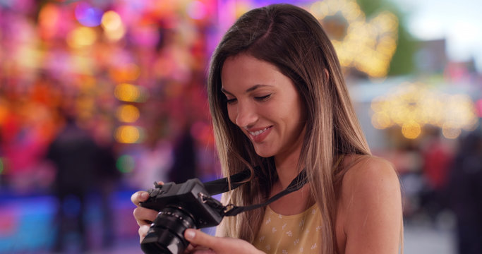 Brunette millennial in her 20s shooting pictures with camera at street carnival