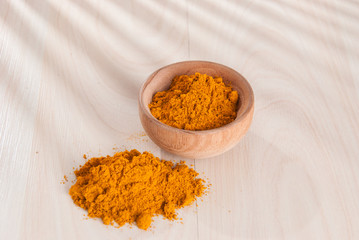Turmeric powder and fresh turmeric on wooden background.