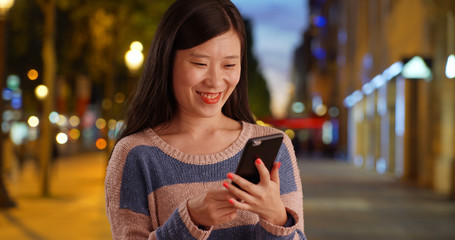 Portrait of young woman using smart phone and sending texts in Paris France
