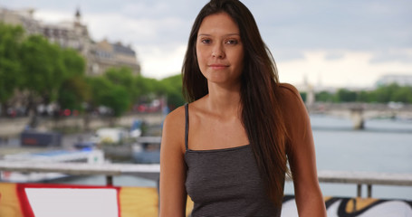Beautiful Caucasian girl wearing striped tank top standing on bridge in Paris