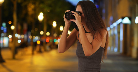 Traveling girl taking picture with dslr camera on the Champs-Elysees at night