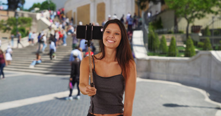 Fototapeta premium Cute millennial girl vacationing Rome taking silly selfies by the Spanish Steps