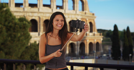 Obraz na płótnie Canvas Cute brunette traveler girl in front of the Roman Coliseum using selfie stick