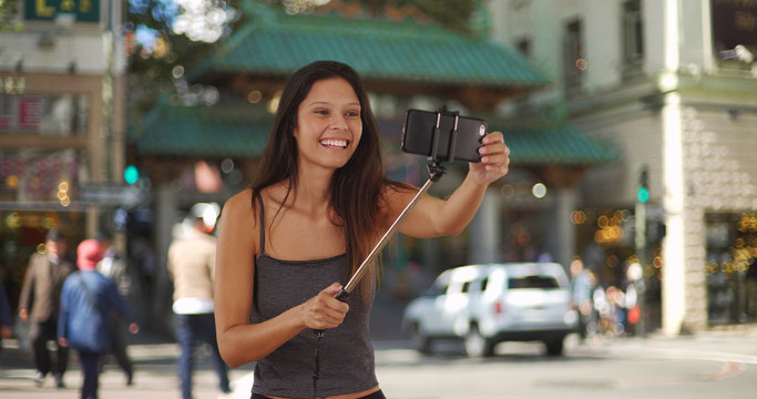 Trendy young tourist woman using selfie stick in Chinatown San Francisco