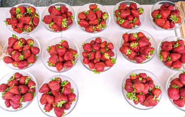 Fresh organic strawberries on display at a farmers market in New Zealand, NZ - plastic-free presentation in glass bowls viewed from above