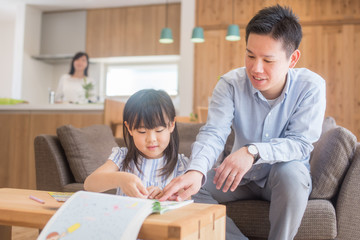リビングで娘に勉強を教えるお父さん
