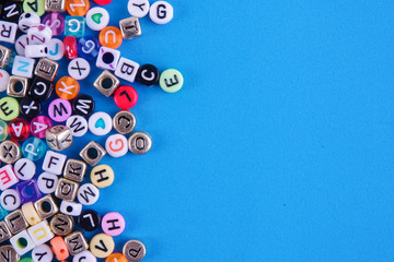 Colorful plastic alphabet dice on a blue background as a background. - obrazy, fototapety, plakaty