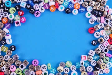 Colorful plastic alphabet dice on a blue background as a background.