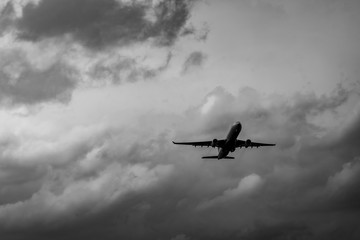 Commercial airplane on grey sky and clouds with copy space. Failed vacation. Hopeless and despair concept. Moody sky and transport plane. Sad emotional scene. Background of aircraft flight.