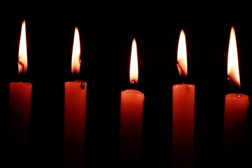  Several candles lit in the dark with the whole black background. Black background highlighting lighted candles leaving a super natural effect