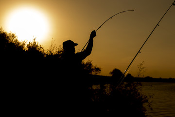 man is fishing at sunset