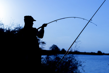 man is fishing at sunset