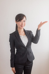 指し示すポーズをするスーツ姿の女性