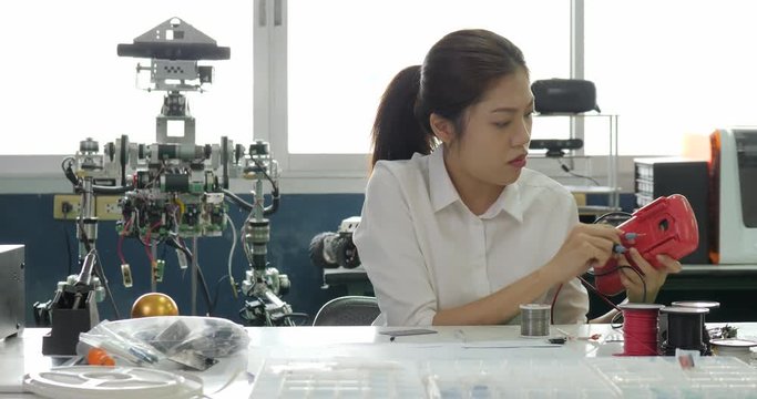 Woman electronics engineer is measuring the signal in the electrical circuit in her workshop. Girl student are studying electronics in classroom.