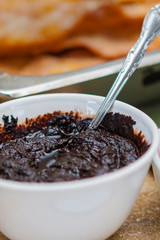 Closeup of a Silver Spoon Dipped in Dark Chocolate Sauce