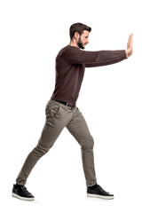A bearded man in casual clothes tries to push a heavy object with both arms with one leg put in...