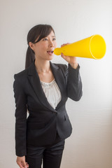 スーツ姿でメガホンを持つ女性