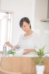 Obraz na płótnie Canvas キッチンで洗い物をする女性