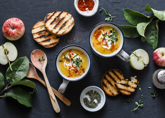 Roasted butternut squash and apples paleo diet vegetarian soup on dark background, top view. Flat lay