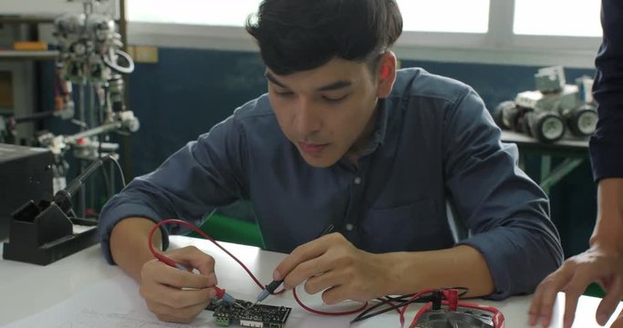 Asian student are studying electronics and measuring the signal in the electrical circuit with their teacher in classroom.
