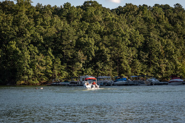 People speed boating in Lake Lanier next to boat house and lakefront properties