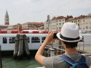 Fototapeta na wymiar young tourist while photographing the bell tower of san marco in