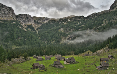 Fototapeta na wymiar Traditional wooden shepherd huts on high alpine meadow in slovenian part of Julian Alps