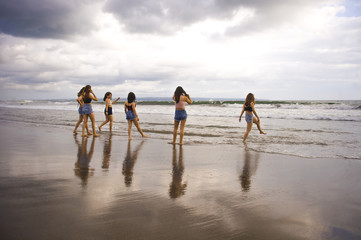 Fototapeta na wymiar group of happy and excited young women enjoying having fun on beautiful sunset beach in girlfriends summer holidays trip together and girls friendship concept