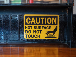 Caution hot surface, do not touch sign in front of a grill at a restaurant 