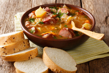 Authentic Czech cabbage soup with sausages and vegetables close-up in a bowl. horizontal