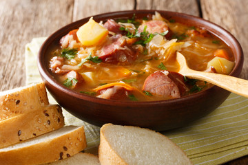 Czech food: Zelnacka cabbage soup with sausages and vegetables close-up in a bowl. horizontal