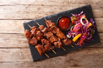 Foto auf Leinwand Recipe of a spicy African suya kebab on skewers with fresh vegetable salad and ketchup close-up. Horizontal top view © FomaA