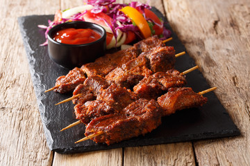 suya kebab with ground peanuts and spices with fresh vegetable salad and ketchup close-up....