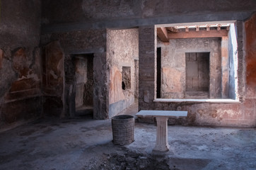 Fototapeta na wymiar The view in the ruin of house in Pompei. It is antique historical city in Italy in Eruope. There is stone table and floor. door and window.
