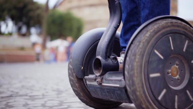 A young guy rides on a segway in a circle, a close-up of the wheels. Scooter goes in the circle.
