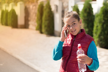 Fototapeta premium Beautiful girl talking on a smartphone in red vest