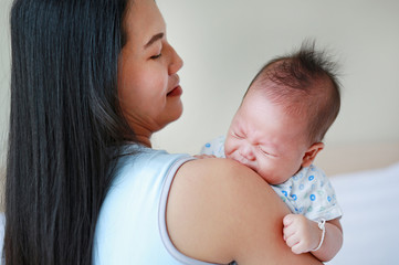 Close up Asian mother carrying infant in the bedroom.