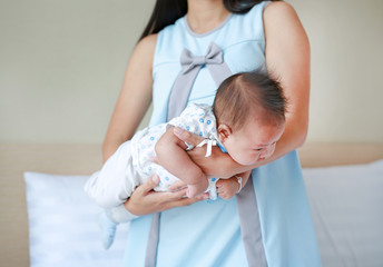 Mother carrying upside down infant baby for decrease baby Flatulence. Baby health care concept.