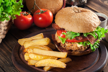 Delicious burger with chicken, bacon, tomato and cheese