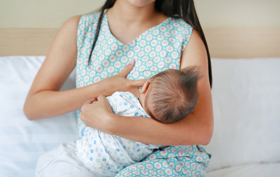Close-up infant baby feeding from mother breast.
