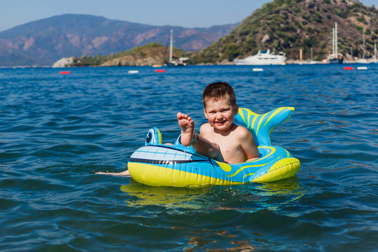 cheerful boy sitting in an inflatable boat on the sea