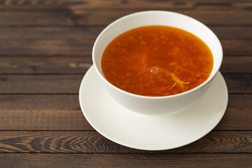 Chicken soup with vegetables and herbs in a white bowl on a wooden table