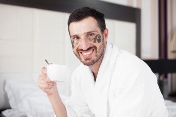 Handsome man drinking morning coffee in the bed