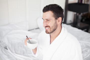 Handsome man drinking morning coffee in the bed