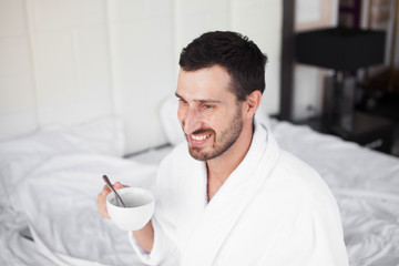Handsome man drinking morning coffee in the bed