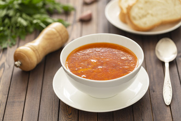 Chicken soup with vegetables and herbs in a white bowl on a wooden table